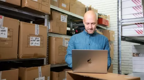 Mand på lager kigger på sin bærbar computer