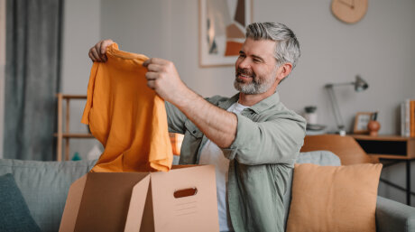 Glad mand åbner pakke med t-shirt